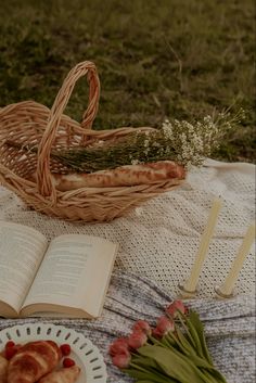 an open book sitting on top of a table next to a basket filled with flowers