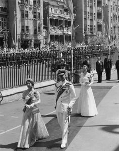 an old black and white photo of people walking down the street