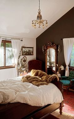 a bedroom with a bed, chair and chandelier hanging from it's ceiling