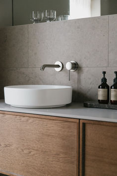 a white sink sitting on top of a counter next to bottles and soap dispensers