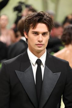 a young man in a tuxedo looks at the camera