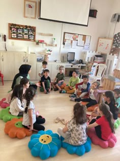 a group of children sitting on the floor in a circle playing with stuffed animal toys