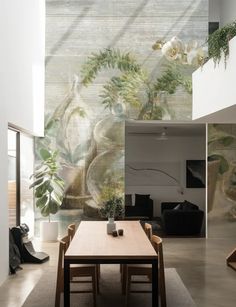 a dining room table and chairs in front of a wall with flowers painted on it