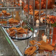 the table is set with orange napkins and place settings for an elegant dinner party