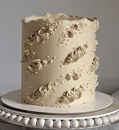 a three layer cake with white frosting and decorative decorations on a silver platter