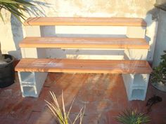 a wooden bench sitting next to a potted plant on top of a brick floor