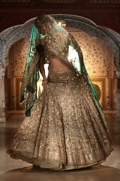 This champagne lehenga set features all over silver-gold zardozi embroidery on an organza base. The contrasting tissue organza dupatta is in an emerald tone with four sided border. From Seema Gujral’s Samode collectionDELIVERY TIMEPlease wait 8-12 weeks for your outfit to arrive.FABRIC DETAILSOrganzaProfessional cleaning only. Sage Green Lehenga Bride, Sage Green Bridal Lehenga, Champagne Lehenga, Sage Green Lehenga, Maroon Dupatta, Seema Gujral, Latest Bridal Lehenga, Mehendi Outfits, Zardozi Embroidery