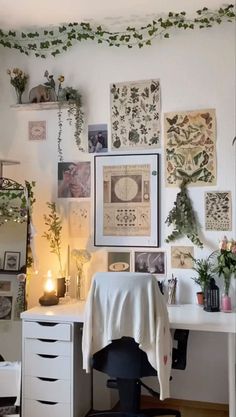 a white desk topped with lots of pictures and plants