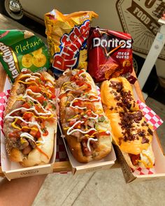 three hot dogs with toppings and chips