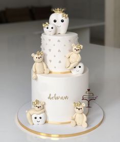 a three tiered white cake with teddy bears on the bottom and gold trimmings