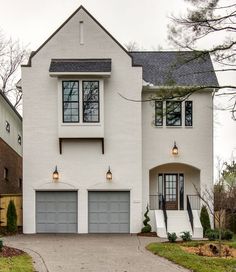 a large white house with two garages on the front and one story above it