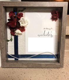 a frame with flowers and a note attached to it