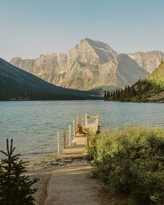 a wooden dock sitting on top of a lake surrounded by mountains