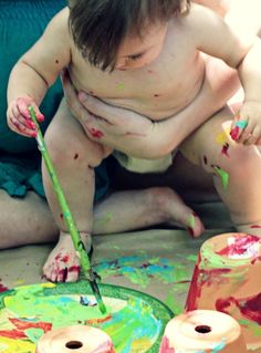 a young boy is painting with paint on his body