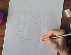 a person is drawing a house with colored pencils