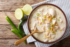 a bowl of chicken and rice soup with a wooden spoon next to some green beans