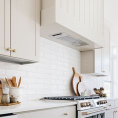 a stove top oven sitting inside of a kitchen next to white cabinets and counter tops