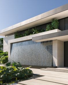 a building with a water feature in front of it and plants growing on the side