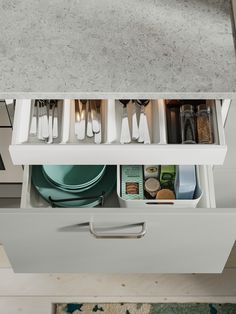 an open drawer with utensils and other items in it on a counter top