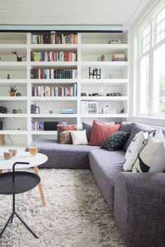 a living room filled with furniture and bookshelves next to a large white window