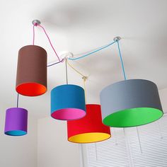 three different colored lamps hanging from the ceiling in a room with white walls and windows