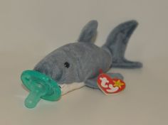 a stuffed shark with a pacifier in it's mouth on a white surface