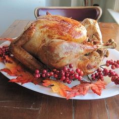 a turkey on a plate with autumn leaves and berries