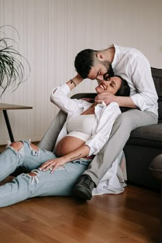 a man and woman sitting next to each other on the floor in front of a couch