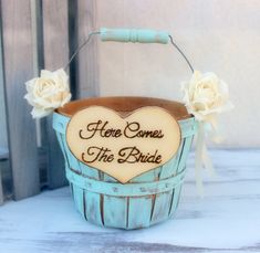 a wooden sign that says here comes the bride in a basket