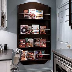 a kitchen with an oven, microwave and shelves filled with cookbooks on the wall