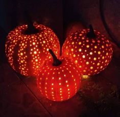 three pumpkins with holes on them are lit up in the dark, and there is no image to provide a caption for