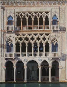 an old building with many windows and balconies on the front, next to a body of water