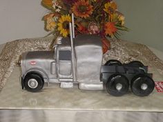 a silver toy truck sitting on top of a table next to a vase with flowers