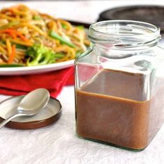 a glass jar filled with brown liquid next to a plate of food