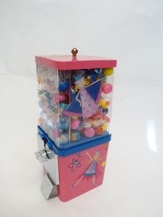 a pink and blue gummy machine on a white surface with lots of candies in it