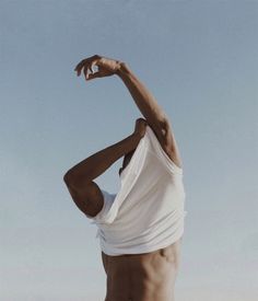 a man in white shirt and shorts standing on beach with his arms stretched out to the side