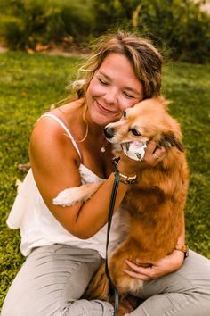 a woman sitting on the ground holding a dog