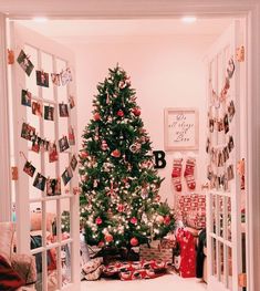 a decorated christmas tree sitting in the corner of a room with pictures on the wall