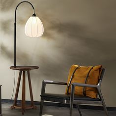 a chair, table and lamp in a room with a wall painted white behind it