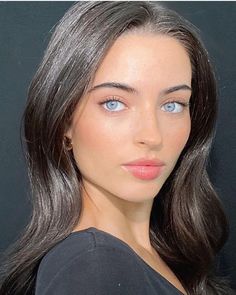 a woman with long hair and blue eyes is posing for the camera in front of a black background