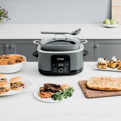 a table topped with plates of food next to an electric pressure cooker on top of a counter