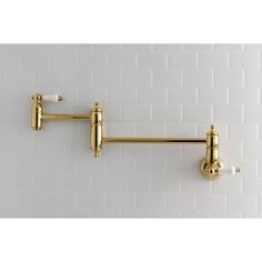 two brass - plated hooks hang on a white tile wall