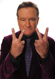 a man in a purple suit making the peace sign with his hands while wearing a ring