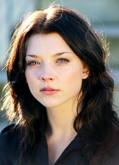 a close up of a person wearing a black shirt and looking at the camera with a serious look on her face