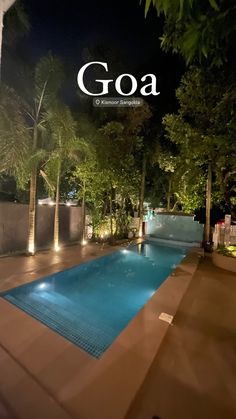 an outdoor swimming pool surrounded by greenery and trees at night with the word goa above it