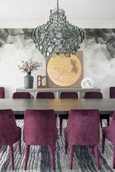 a dining room table with purple chairs and a chandelier hanging from the ceiling