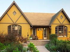 a yellow house with two large windows and steps leading up to the front door area