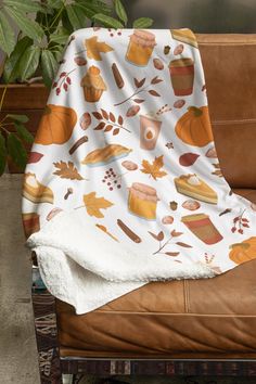 a blanket is sitting on the back of a leather chair next to a potted plant