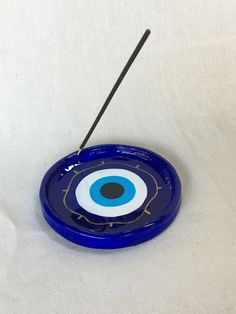 a blue plate with an evil eye on it and a black stick sticking out of the center