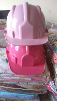 a pink plastic construction helmet sitting on top of a pile of fabric and other items